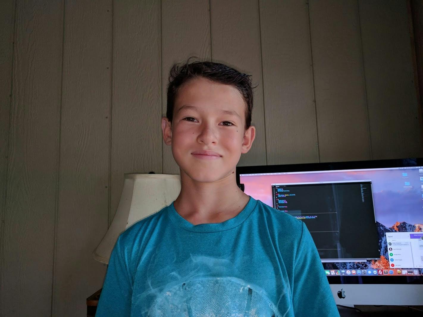 Moses Finlay at age 12 in front of a computer showing code.